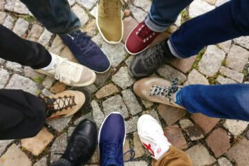 Circle of sneakers on cobblestone pavement representing diversity and urban fashion.